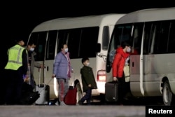 FILE - Australian evacuees from China's Wuhan, the epicenter of the coronavirus epidemic, board a bus after arriving at the airport on Christmas Island, Australia, Feb. 6, 2020.