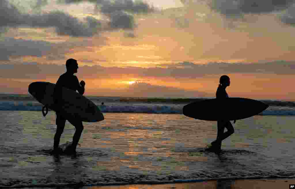 غروب آفتاب و موج سواران در ساحل بالی در اندونزی.