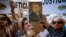 A woman sings the Argentine national anthem while holding a portrait of the late prosecutor Alberto Nisman outside the AMIA Jewish community center in Buenos Aires, Argentina, Jan. 21, 2015.