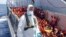 FILE - Migrants wait to be boarded on the San Giusto Navy ship, along the Mediterranean sea, off the Sicilian island of Lampedusa,, Aug. 23, 2014. 