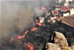 In this photo issued by Cabildo de Gran Canaria, flames from a forest fire burn close to houses in El Rincon, Tejeda on the Spanish Gran Canaria island on Sunday Aug. 18, 2019.