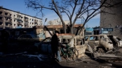 Un hombre con una bicicleta se encuentra cerca de coches quemados después de un ataque en Dobropillia, región de Donetsk, el 8 de marzo de 2025, en medio de la invasión rusa de Ucrania.