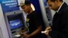 Men withdraw cash from automated teller machines at a Mercantil bank branch in Caracas, Venezuela, Aug. 20, 2018. 