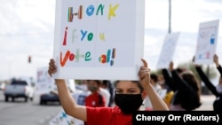 Seorang siswa memajang spanduk yang mendorong pengendara untuk memberikan suara pada sore hari pemilihan presiden di South Tucson, Arizona, AS, 3 November 2020. (Foto: REUTERS/Cheney Orr)