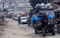 Syrians drive through the city of al-Mastouma in Idlib province as they flee a government offensive, Jan. 28, 2020.