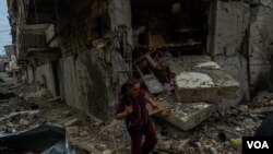 A woman walks through a housing complex destroyed in recent battles in Nagorno-Karabakh, Oct. 10, 2020. (Yan Boechat/VOA)