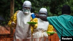 FILE - Medical staff working with Doctors Without Borders prepare to take food to patients in the isolation area of an Ebola treatment center in Sierra Leone's Kailahun district.