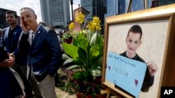 Bill Richard, second from left, father of Boston Marathon bombing victim Martin Richard, stands next to a painting of Martin, right, at the conclusion of groundbreaking ceremonies for a park named after his late son, Aug. 16, 2017, in Boston. Martin Richard, 8, was the youngest of three people killed when two bombs exploded near the Boston Marathon finish line on April 15, 2013.