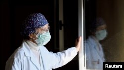 FILE - Laura Ricevuti, the medical doctor who diagnosed the first case of COVID-19 in an Italian patient with Dr. Malara, looks through the window at Codogno Hospital, Feb. 11, 2021. 