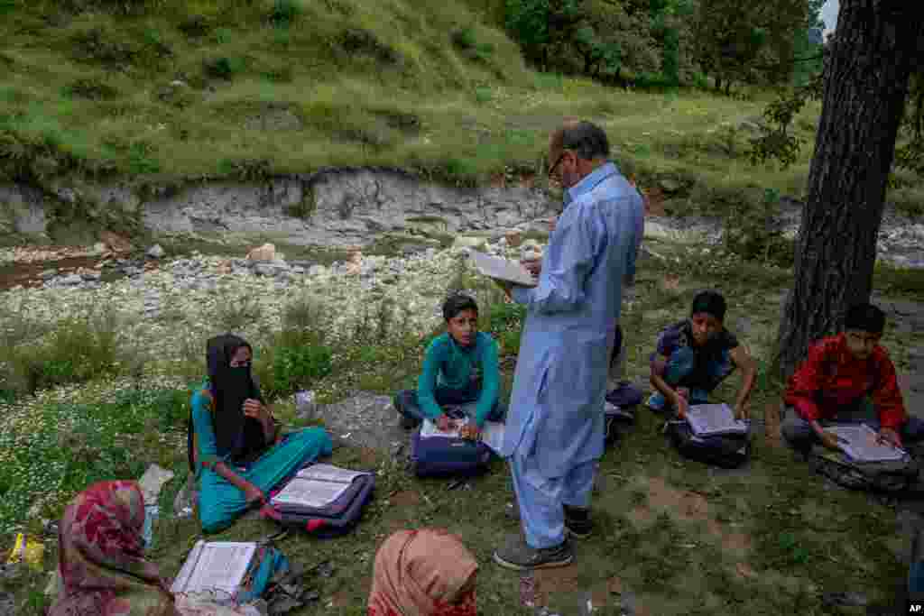 Kashmiri students listen to their teacher Ghulam Hassan during open air community classes in Tangmarg area northwest of Srinagar, Indian-controlled Kashmir.