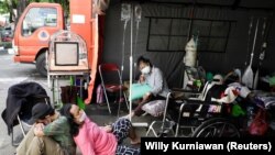 Seorang pasien COVID-19 beristirahat di tanah di luar tenda darurat yang didirikan di luar rumah sakit di tengah lonjakan kasus COVID-19 di Bekasi, 25 Juni 2021. (Foto: Willy Kurniawan/Reuters)