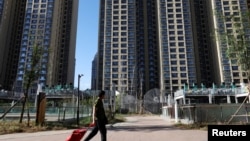 资料照：2023年9月27日，中国北京，一名男子拉着手推车经过恒大住宅区的住宅楼。（路透社）
