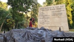 Seorang wisatawan membaca nama-nama korban kekejama n PKI di Monumen Kresek, Madiun. (Foto:VOA/ Nurhadi)