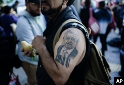 Seorang pendukung Presiden Meksiko Andres Manuel Lopez Obrador dengan tato presiden, berkumpul dengan orang lain sebelum pawai untuk mendukung pemerintahan Lopez Obrador, di Mexico City, Minggu, 27 November 2022. (Foto: AP/Eduardo Verdugo )