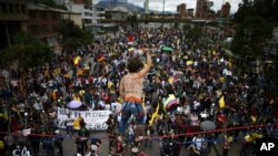 A tightrope artist stands over demonstrators as they march during an anti-government protest in Bogota, Colombia, May 12, 2021. 