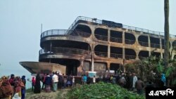 ঢাকা থেকে ২৫০ কিলোমিটার (১৬০ মাইল) দক্ষিণে ঝালকাঠিতে আগুনে পুড়ে যাওয়া একটি ফেরির দিকে তাকিয়ে রয়েছেন গ্রামবাসীরা। (ছবি-এএফপি)