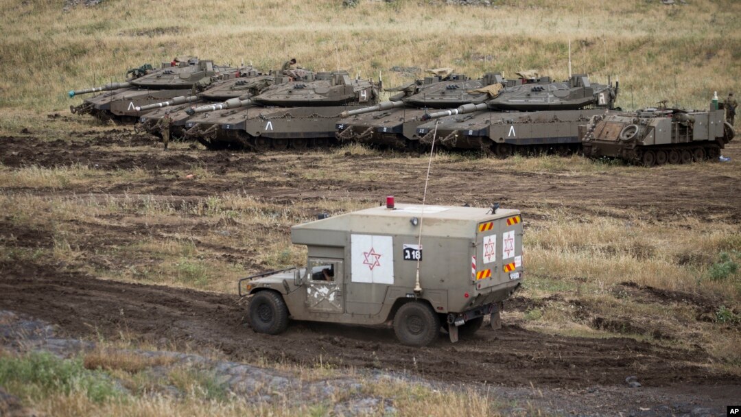 Sebuah ambulans militer Israel melewati tank-tank yang disiagakan di Dataran Tinggi Golan, dekat perbatasan Suriah, Kamis (10/5).