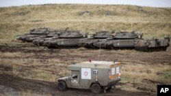 Sebuah ambulans Israel melintasi deretan tank yang disiagakan di dataran tinggi Golan, dekat perbatasan Suriah, 10 Mei 2018.