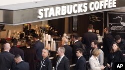 FILE - Customers line up at a Starbucks in New York, April 2, 2015. 