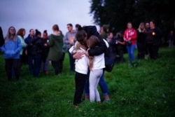 A woman embraces two children during a vigil for the victims of the Keyham mass shooting in Plymouth, England, Aug. 13, 2021.