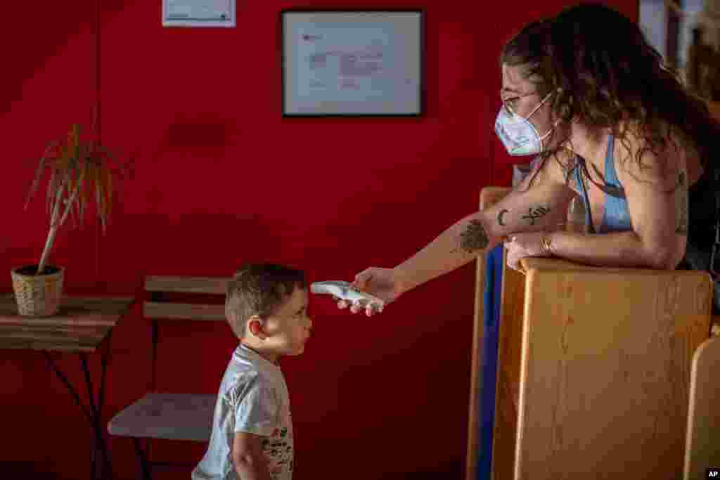 Hugo, 3, has his temperature taken by a teacher as he arrives at Cobi kindergarten in Barcelona, Spain.