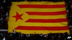 Protesters hold a Catalan flag as they gather outside the National Police Headquarters during a one-day strike in Barcelona, Spain, Oct. 3, 2017.