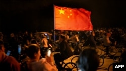 A cyclist waves a Chinese flag as thousands of college students ride on Zhengkai Road in Zhengzhou, in northern China's Henan province, Nov. 9, 2024.