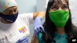 Una enfermera inocula a un trabajador de la salud con una dosis de la vacuna Sinopharm COVID-19 en un centro de salud del programa de salud del gobierno Barrio Adentro, en Caracas, Venezuela, el domingo 7 de marzo de 2021.