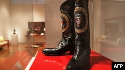 FILE - A pair of Ronald Reagan's cowboy boots sit in a case at Christie's prior to an auction in New York, Sept, 16, 2016. The boots sold Friday for $199,500.