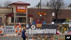 FILE - Tributes cover the temporary fence around the King Soopers grocery store in which 10 people died in a mass shooting in late March in Boulder, Colorado, April 23, 2021.