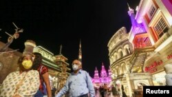 People wear protective masks, following an outbreak of coronavirus, as they walk at Global Village in Dubai, United Arab Emirates, March 10, 2020.