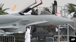 Seorang pengunjung wanita (atas kanan) dan dua orang lainnya mengamati replika pesawat jet tempur Typhoon di hari pertama Pameran Dirgantara "Dubai Airshow" di Dubai (17/11).