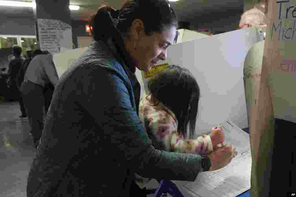 Vesta Avery, 2, helps her mother Alexis Taylor mark her ballot at the Mickey Mantle School, in New York, Nov. 5, 2024.