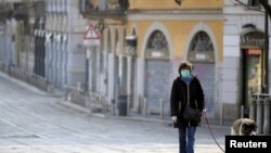  지난 4일 이탈리아 밀라노에서 마스크를 착용한 여성이 반려견을 산책시키고 있다. 