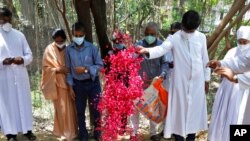 Indian Christian priests and others throw flower petals on the grave of Father Rolfie D'Souza, who died of COVID-19, after his burial at a cemetery in Prayagraj, India, May 15, 2021. 