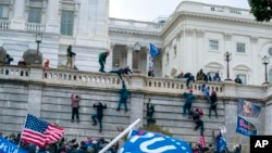 Los partidarios del presidente Donald Trump trepan el muro oeste del Capitolio de Estados Unidos el miércoles 6 de enero de 2021 en Washington. Al regresar al poder, Trump indultó a 1.500 de los asaltantes a la sede legislativa estadunidense.