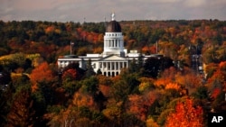 FILE - The State House is surrounded by fall foliage in Augusta, Maine, Oct. 23, 2017. Recent leaf-peeping seasons have been disrupted by weather conditions in New England, New York and elsewhere.