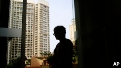 FILE - Bilqis checks her phone as she poses for a photograph in Mumbai, India, June 8, 2016. The slender 50-year-old doctor defends what is widely known as female genital mutilation within her small, prosperous Dawoodi Bohra community in India, saying it’s a mild version that amounts to “just a little nick. No harm done.” Yet she also acknowledges regret and guilt at putting her daughter through a practice the United Nations calls a violation of girls’ rights. 