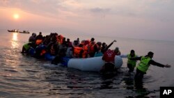FILE - volunteers help migrants and refugees on a dingy as they arrive at the shore of the northeastern Greek island of Lesbos, after crossing the Aegean sea from Turkey.