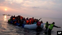 FILE - volunteers help migrants and refugees on a dingy as they arrive at the shore of the northeastern Greek island of Lesbos, after crossing the Aegean sea from Turkey.