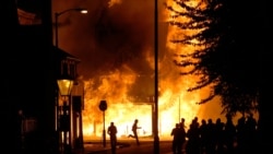 Rioters run through the streets of the Croydon area of south London as a shop burns