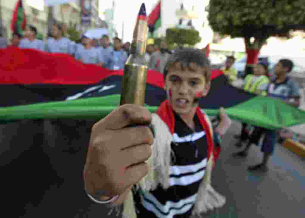 A boy holds a bullet while attending a rally where protesters were calling on the International Criminal Court to issue arrest warrants for Libyan leader Moammar Gadhafi, near the courthouse in Benghazi, Libya, May 14, 2011