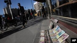 FILE - Iranian banknotes are displayed by a vendor at the side walk of the Ferdowsi Street in Tehran, Jan. 23, 2013.