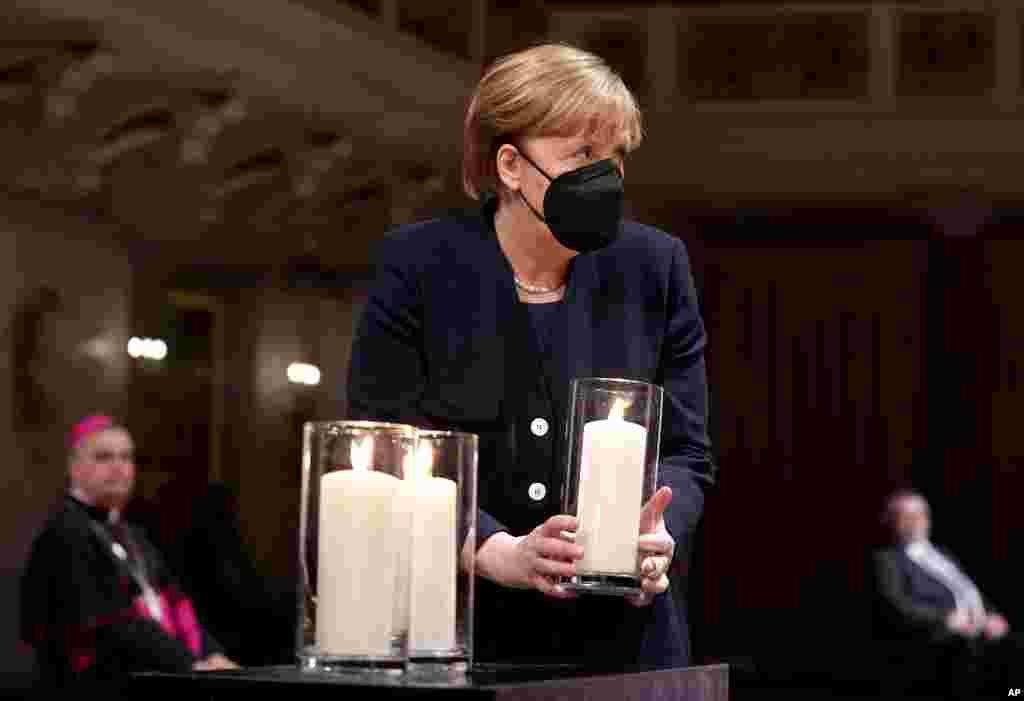 German Chancellor Angela Merkel holds a candle during a memorial service in Berlin, in remembrance of the country&#39;s COVID-19 dead.