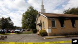 FILE - Area residents and church members look on as authorities investigate a fire at Hopewell Baptist Church in Greenville, Mississippi, Nov. 2, 2016. "Vote Trump" was spray-painted on an outside wall of the African-American church.