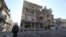 A fighter of Free Syrian Army's Tahrir al Sham brigade walks in front of building destroyed during yesterdays Syrian Air force air strike in Mleha suburb of Damascus January 21, 2013.