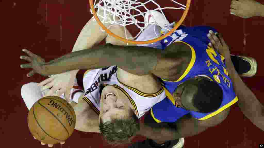 Timofey Mozgov (20) milieu des Cavaliers de Cleveland est bloqué par Draymond Green (23) avant de Golden State Warriors au cours de la première mi-temps du 6e match des finales de basketball de la NBA de Cleveland, mardi 16 Juin 2015.