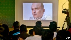 FILE - Journalists look a image of Indian naval officer Kulbhushan Jadhav, arrested in March 2016, during a press conference by Pakistan's army spokesman and the Information Minister, in Islamabad, Pakistan. 