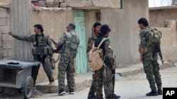 FILE - This photo provided by the Syrian Democratic Forces shows fighters from the SDF patrolling in the northern town of Tabqa, Syria, April 30, 2017. 