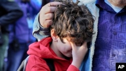 Palisades Charter Elementary School third grade student Jaden Koshki cries in his father's arm upon arriving at his new school, the Brentwood Elementary Science Magnet school in the Brentwood section of Los Angeles, Jan. 15, 2025.